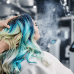 Une femme aux cheveux bleus et verts se sèche les cheveux.