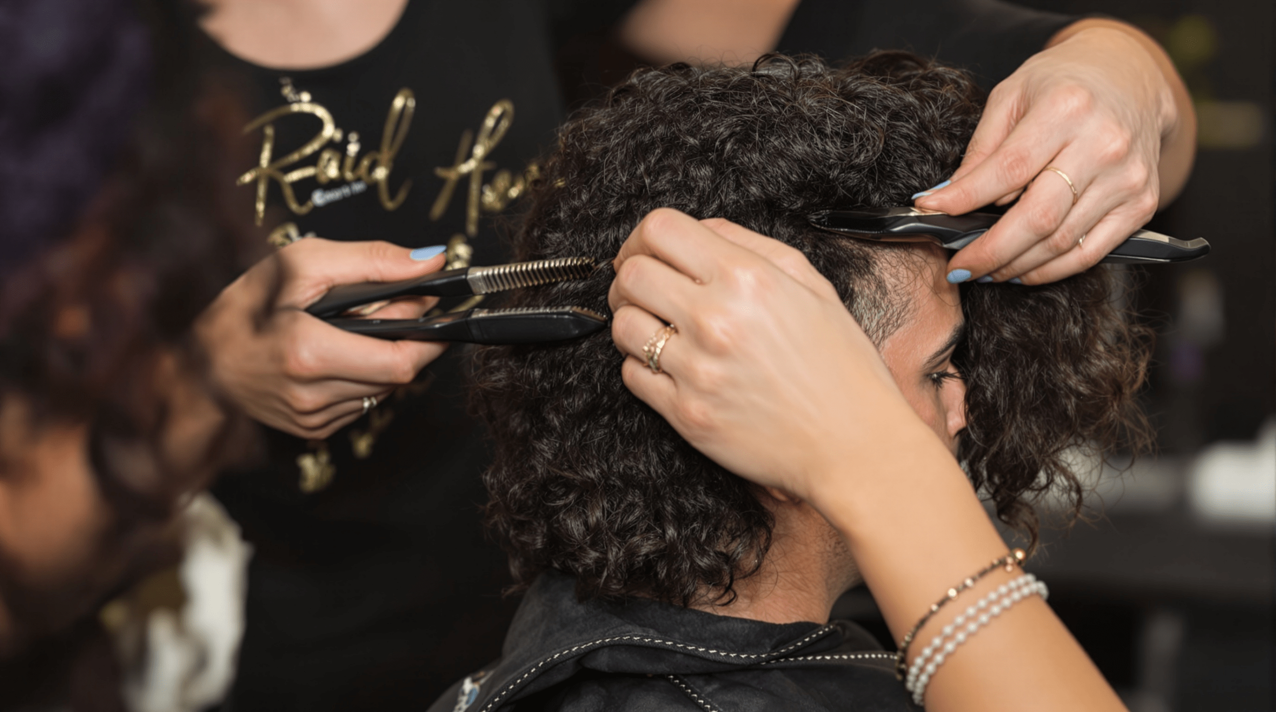 une femme coupe les cheveux d'une autre femme avec une paire de ciseaux